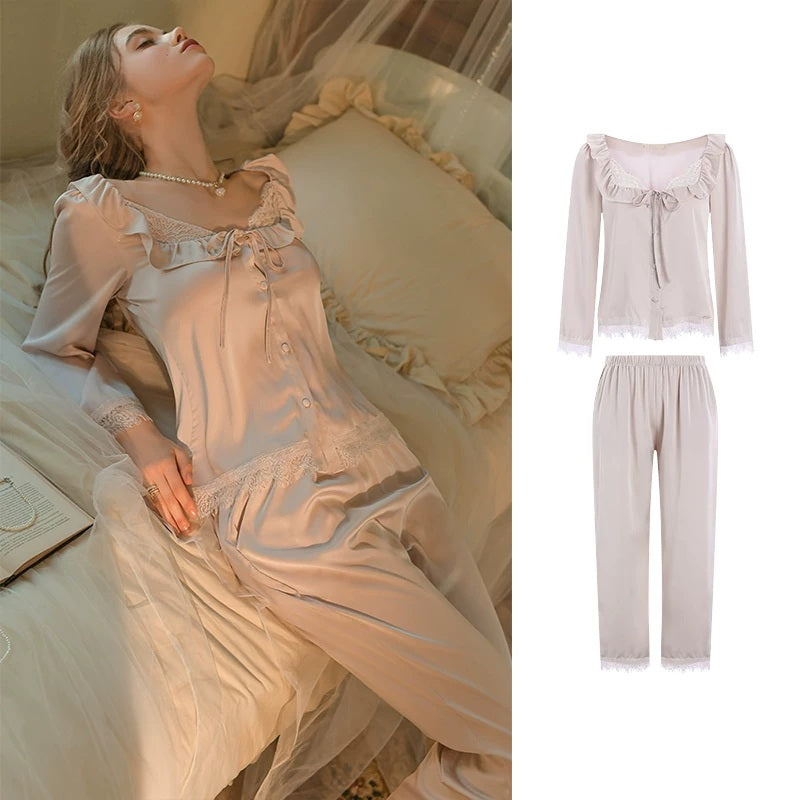 A women's two-piece sleepwear set shown on a model lying on a bed, with a separate inset on the right showing the top and pants laid out against a white background. The set appears in a soft blush pink or pale peach satin-like fabric with ruffled trim, lace details, and long sleeves.