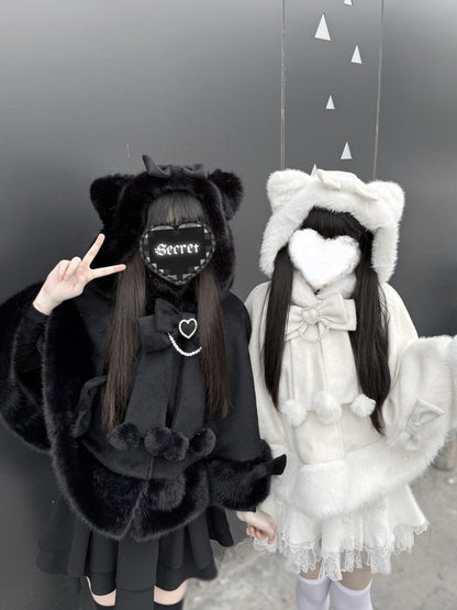 Two people in black and white outfits with fur accents against a gray background.