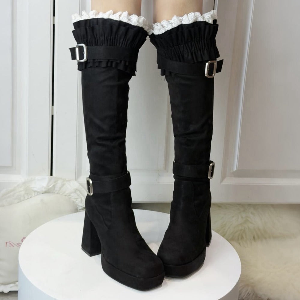 Black knee-high boots with ruffled tops on a white platform.