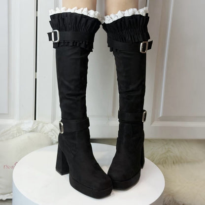 Black knee-high boots with ruffled tops on a white platform.