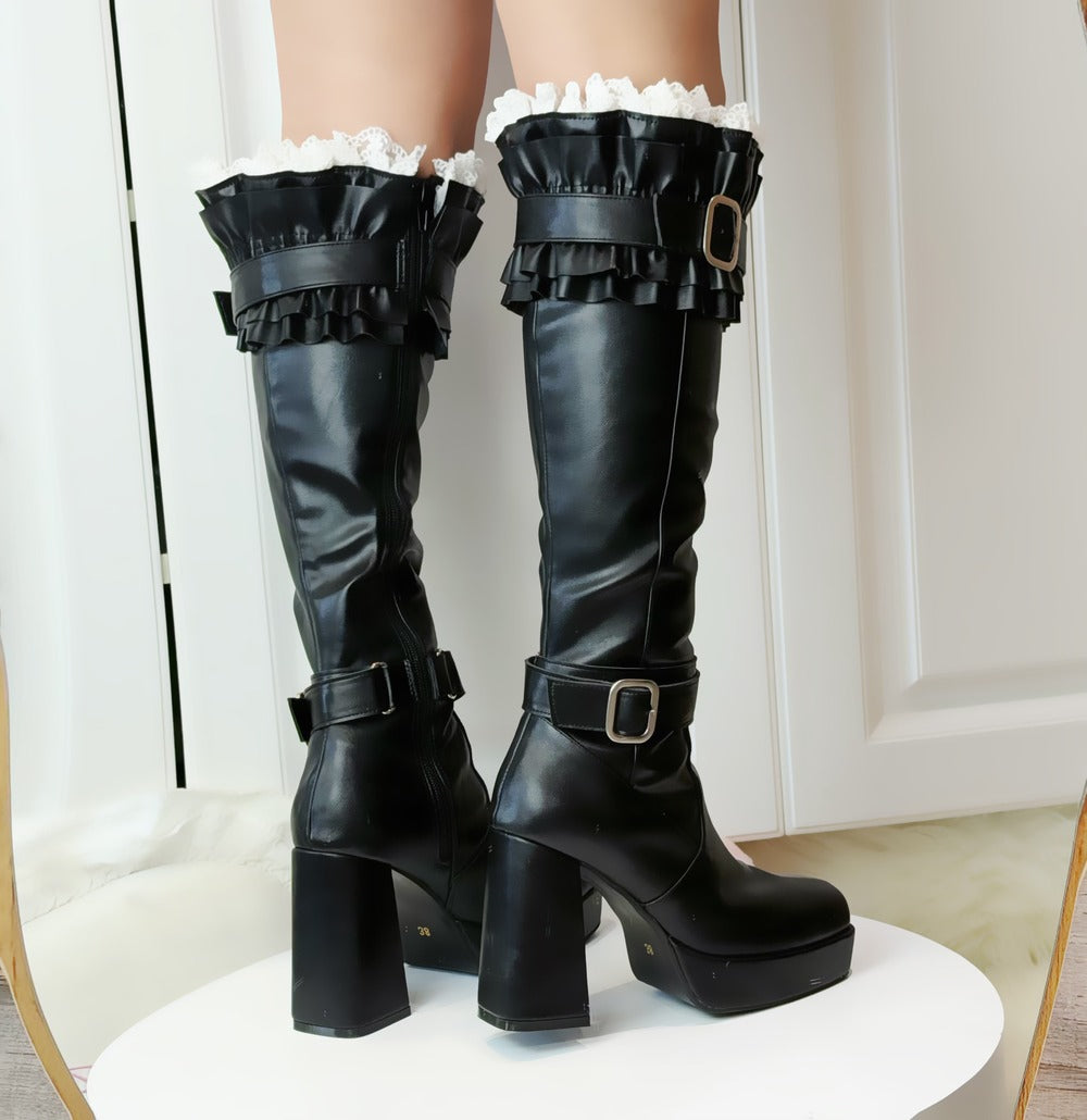 Black knee-high boots with ruffles on a white background