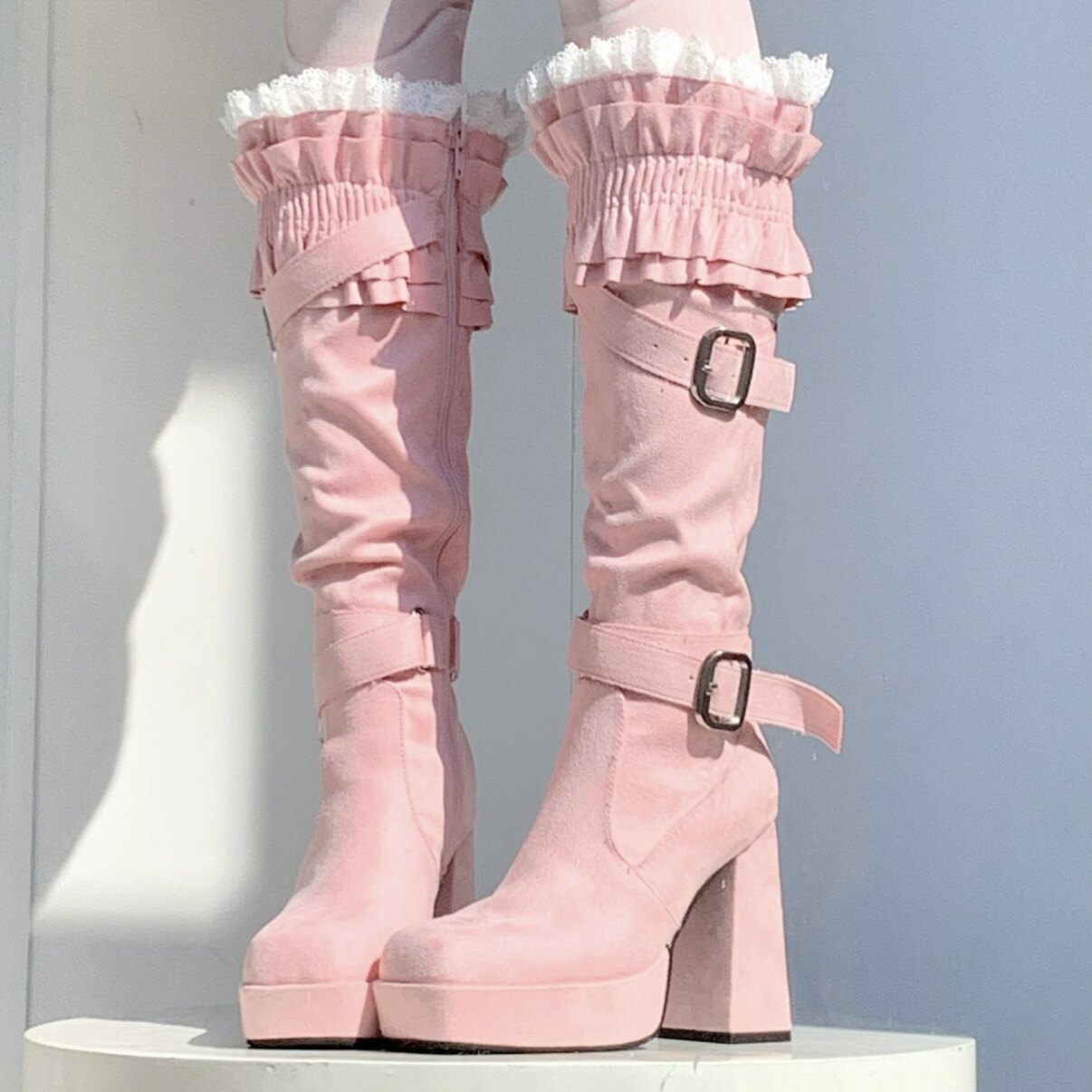 Pink platform boots with ruffled details on a white background