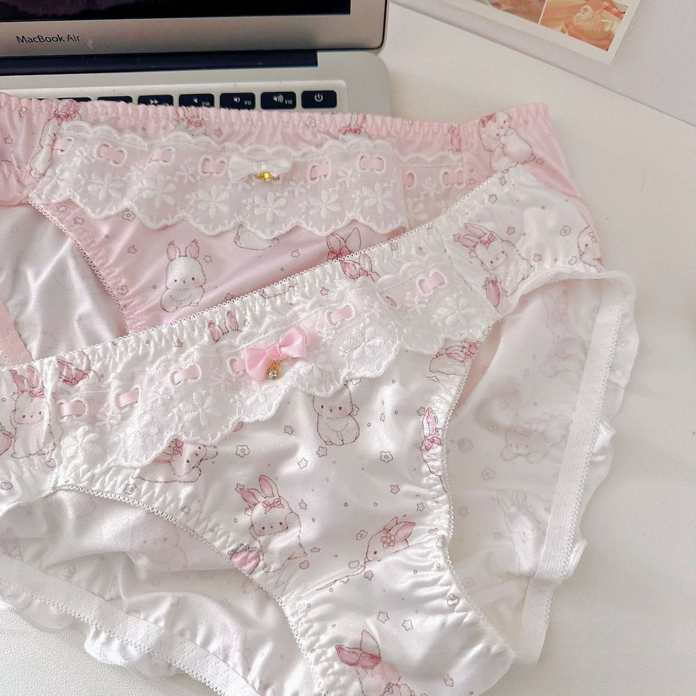 Pair of white underwear with pink floral and cat print on a white surface.