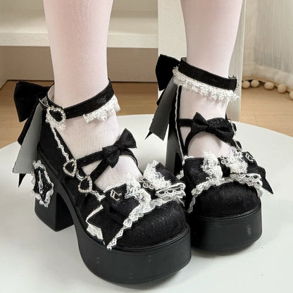 Black platform shoes with lace and bow details worn indoors.
