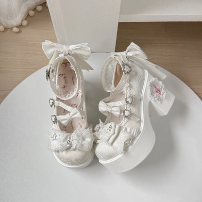 Pair of white children's shoes with decorative bows and flowers on a white surface.