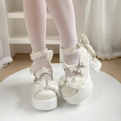 White lace-up shoes with bows worn by a person on a white surface.