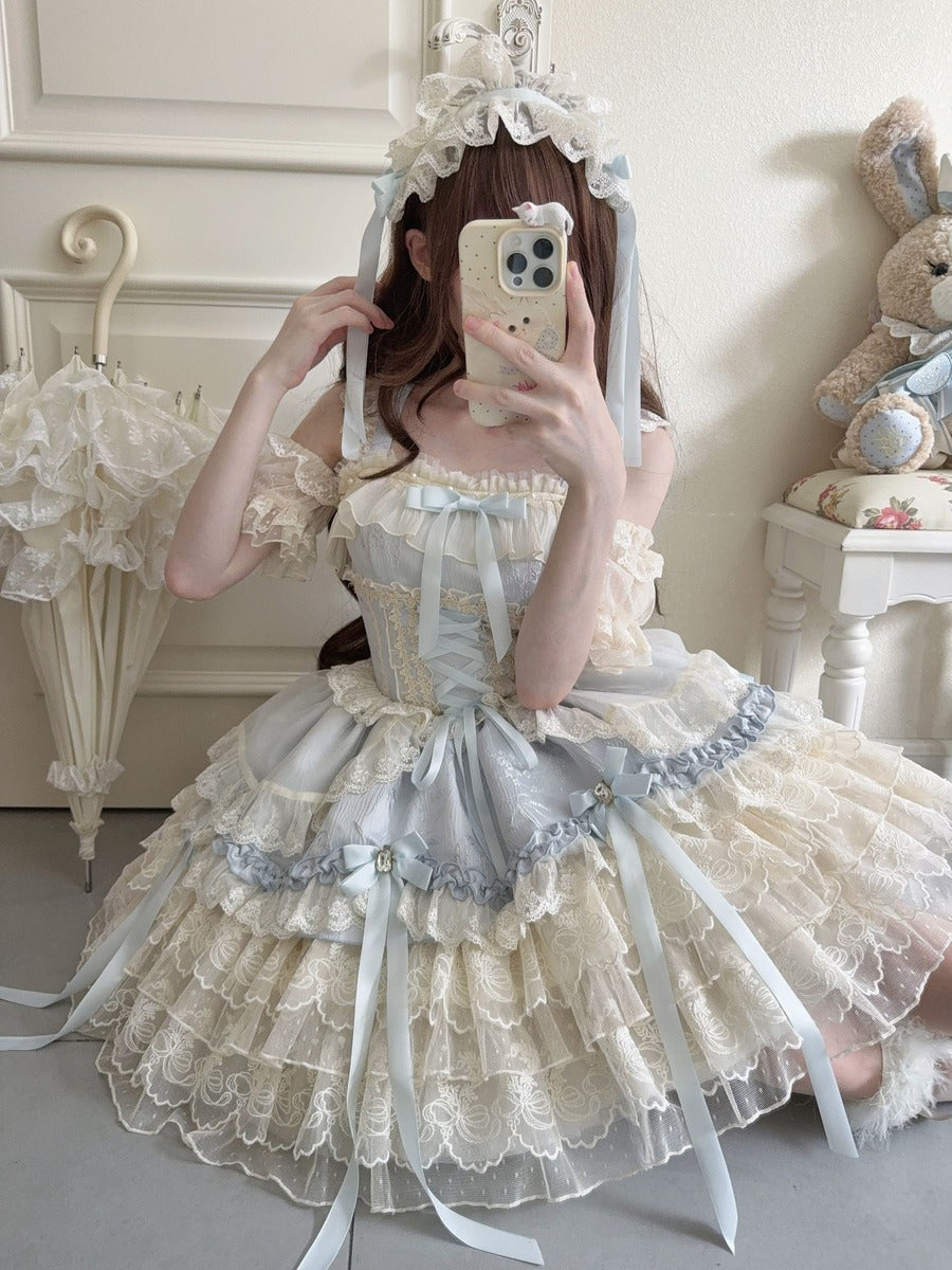 Person wearing a detailed white and gray dress with ruffles in a room.