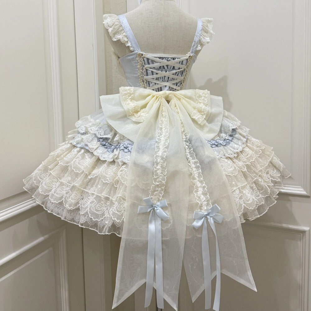 Delicate lace dress with a large bow on a mannequin against a white wall.