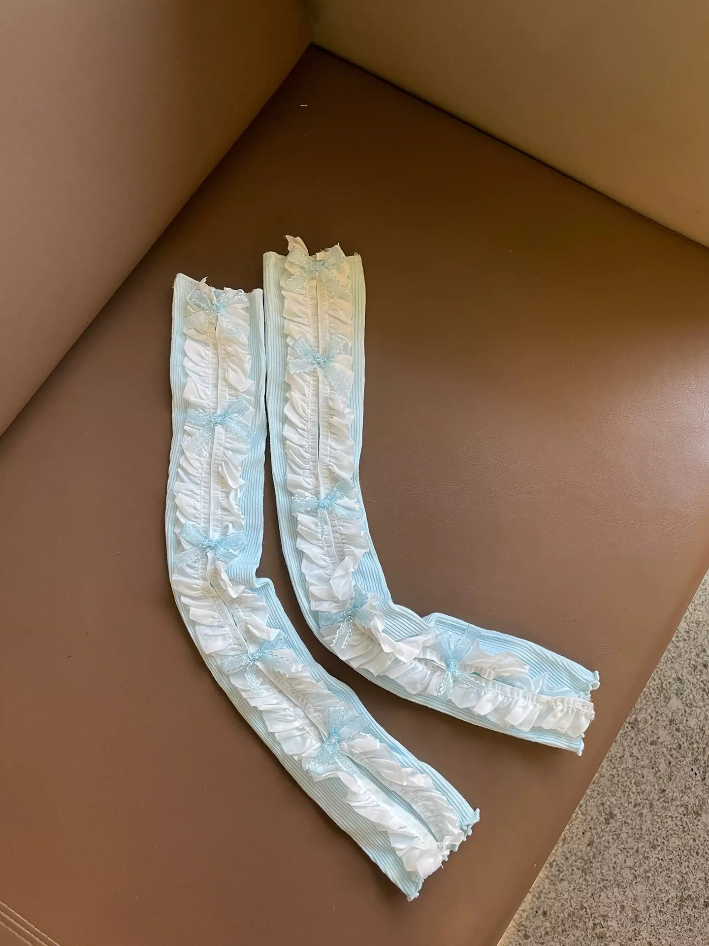 Two white arm warmers on a brown surface