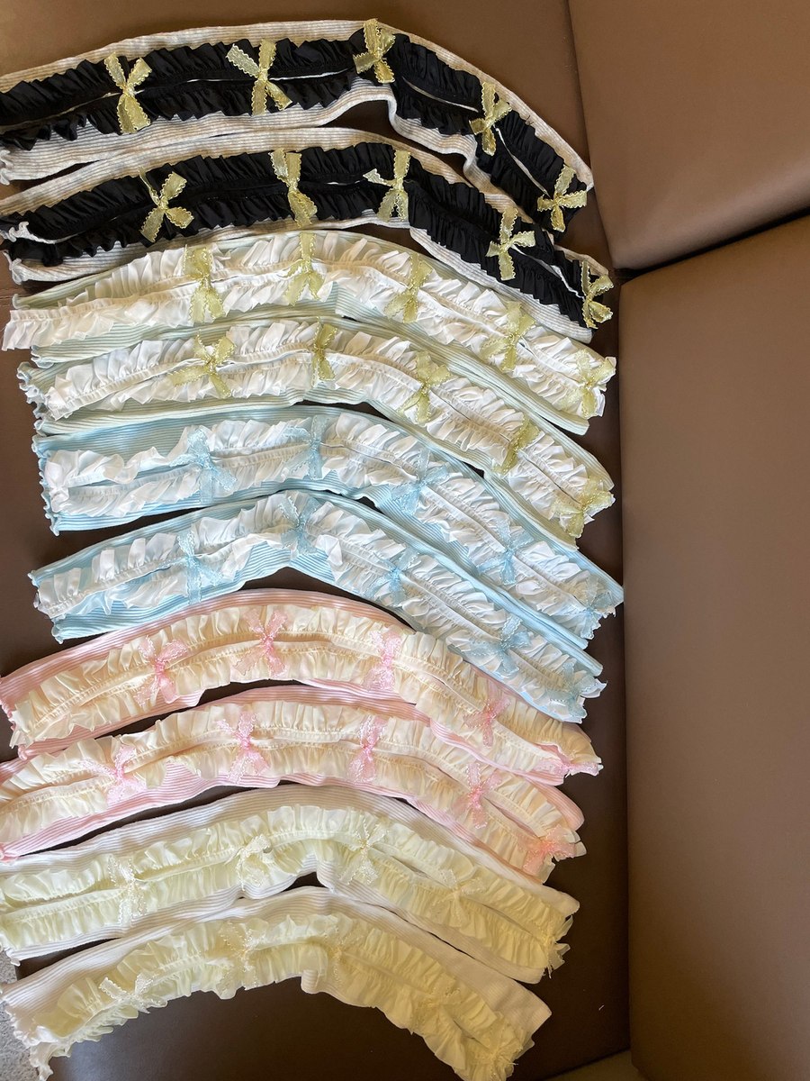 Stack of pastel-colored lace pet collars on a brown surface