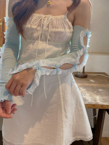 Person wearing a light blue dress with ruffled sleeves in an indoor setting.