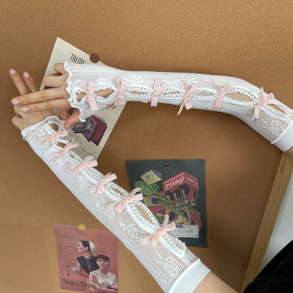 White lace arm cover with pink bows held by a hand on a brown background