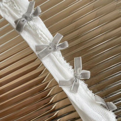 White lace fabric with gray ribbons against a wooden background