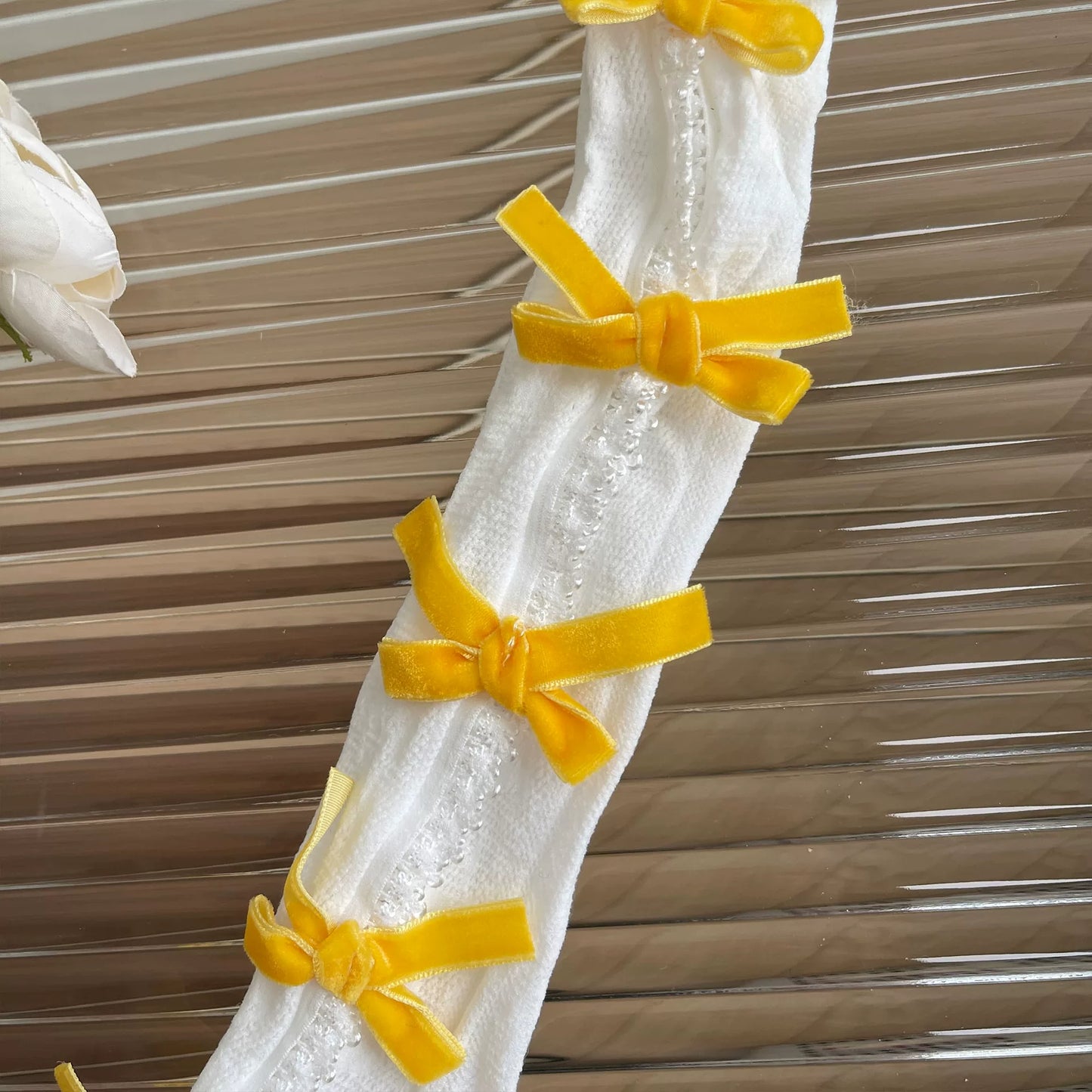 White lace curtain with yellow ribbons against a wooden panel background