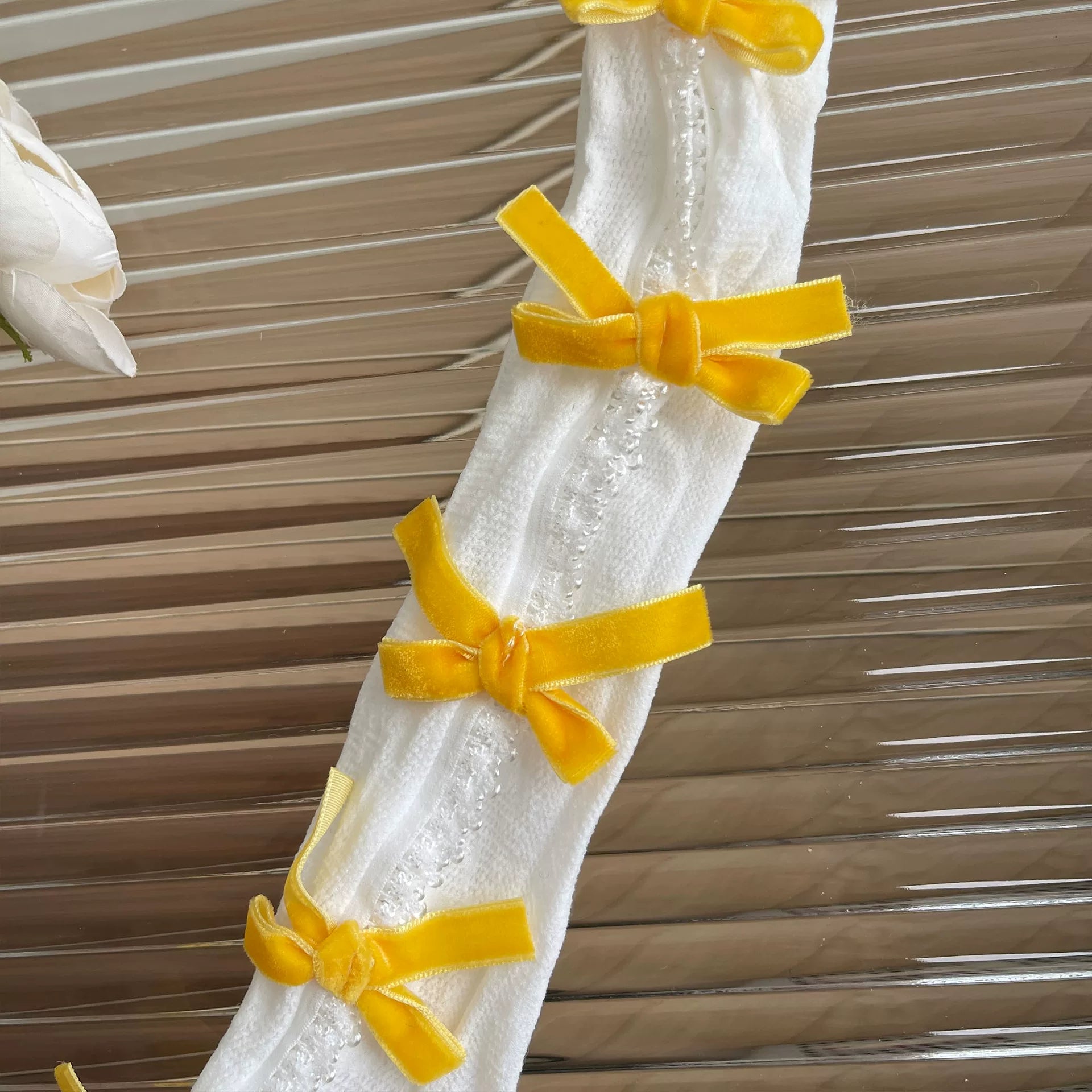 White lace curtain with yellow ribbons against a wooden panel background