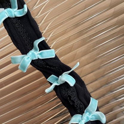 Black lace garment with light blue ribbons on a textured brown background