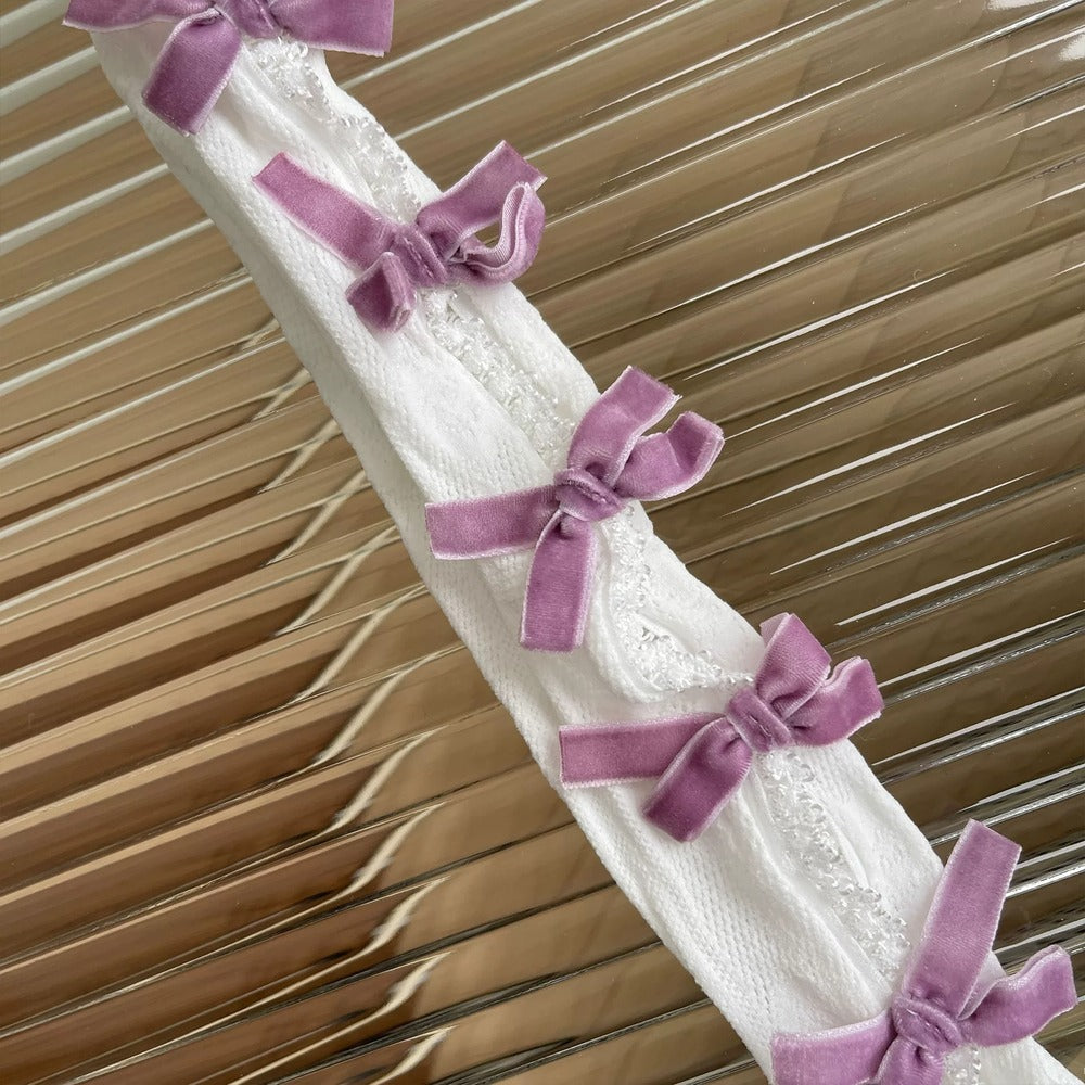 White lace fabric with purple bows against a wooden background