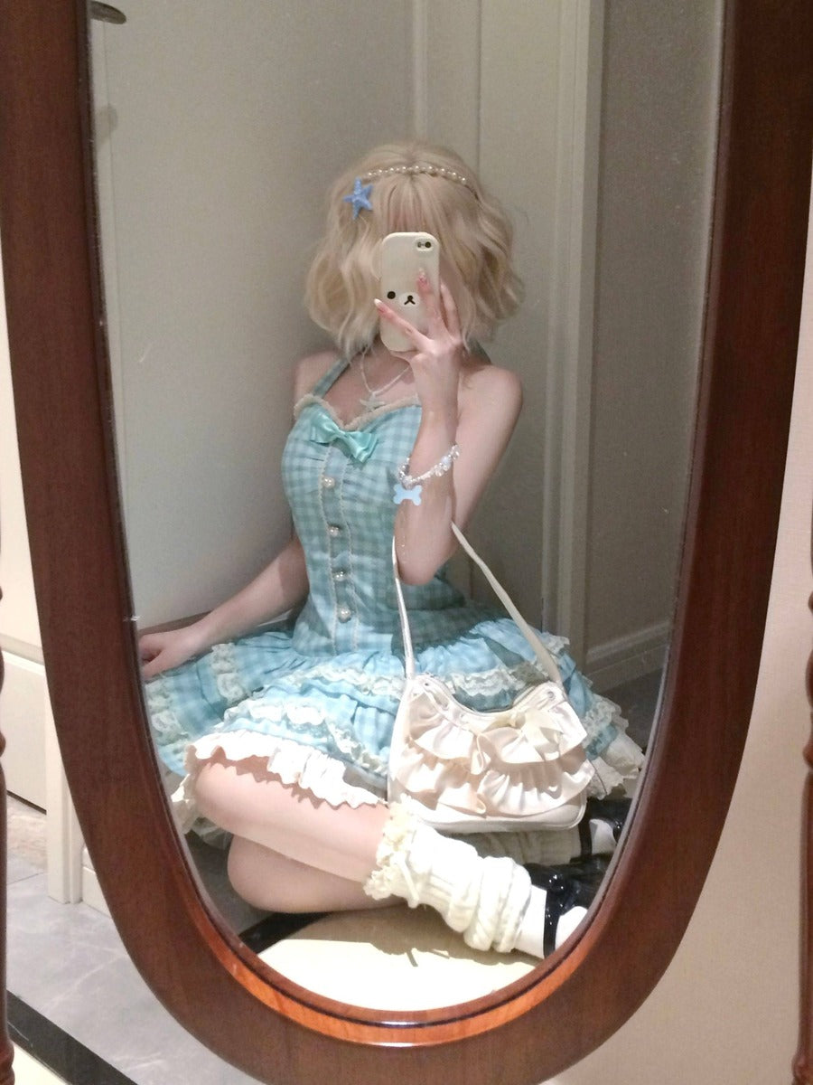 Person wearing a blue checkered dress with white lace details, sitting in front of a mirror.