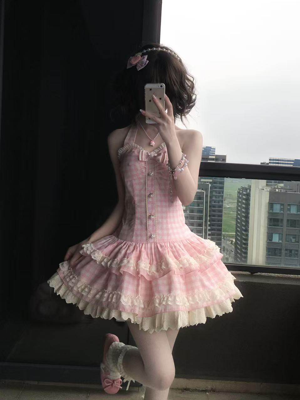 Person wearing a pink and white dress taking a mirror selfie.