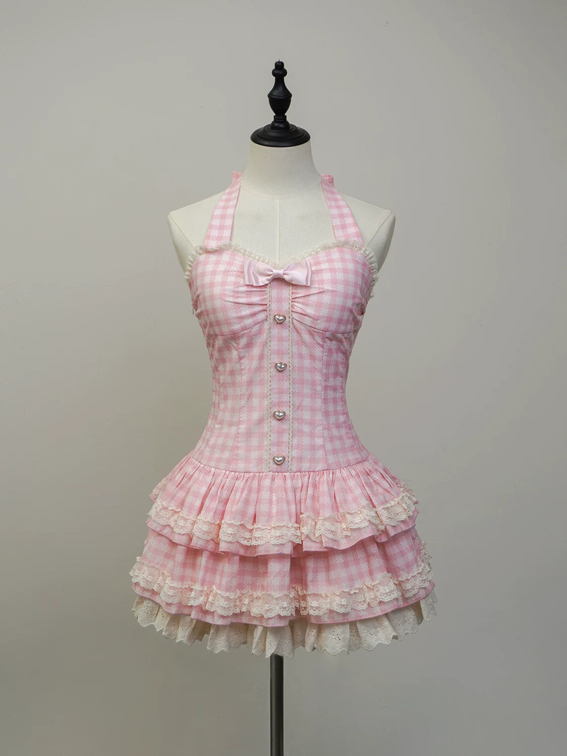 Pink checkered dress with ruffles on a mannequin against a gray background