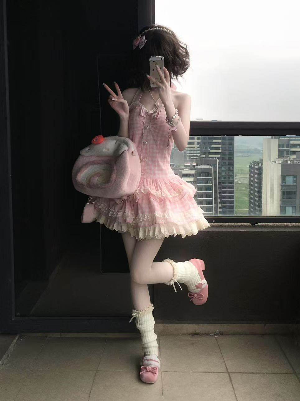 Person in a pink dress with ruffles and white shoes standing in front of a window with cityscape view.