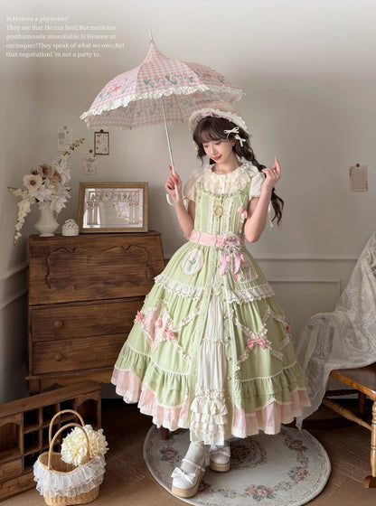 Woman in a green and pink Lolita dress holding an umbrella in a room with wooden furniture and decorative items.