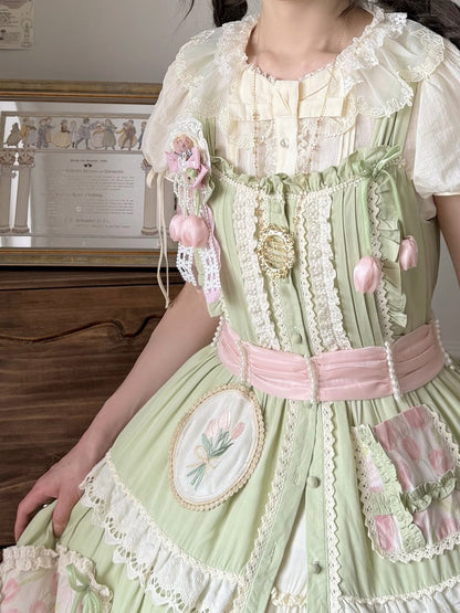 Close-up of a person wearing a detailed green and pink dress with lace and embroidery.