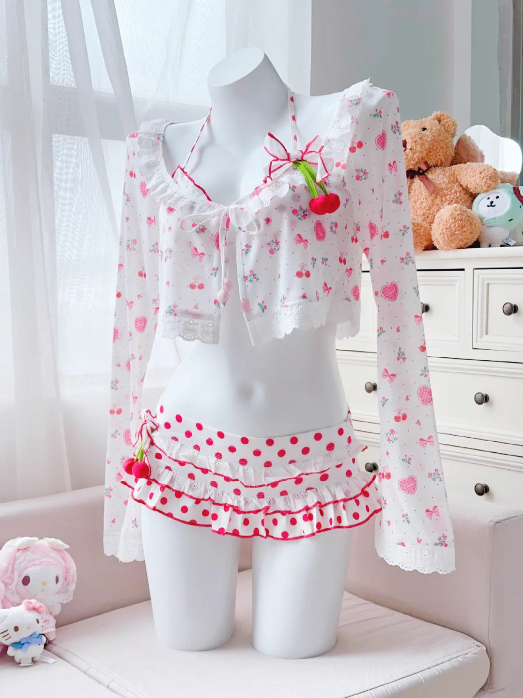 White mannequin wearing a polka dot dress with cherry design in a room setting.