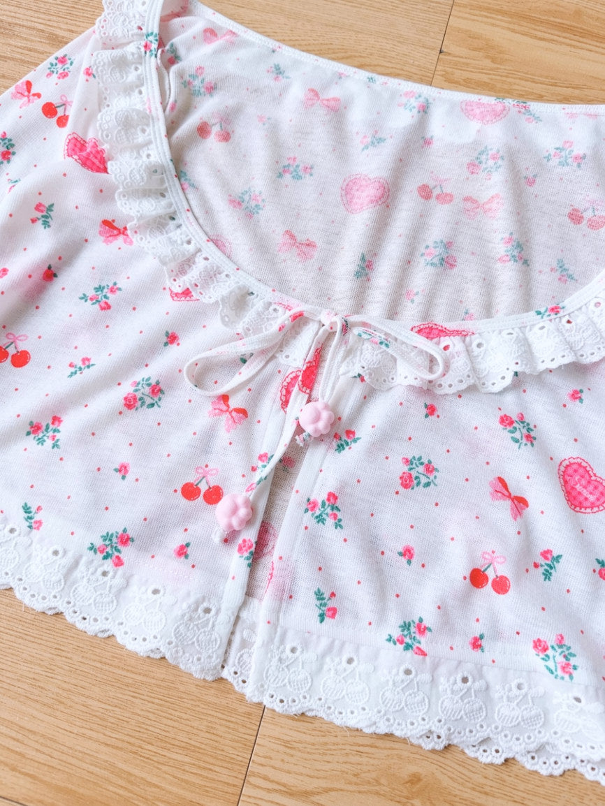 White lace-trimmed garment with floral and cherry pattern on a wooden surface