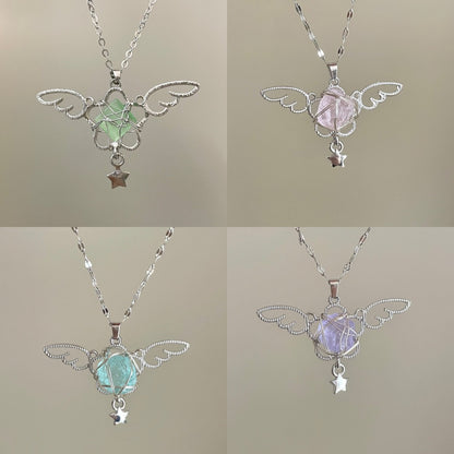 Four angel wing pendants with gemstones on a neutral background