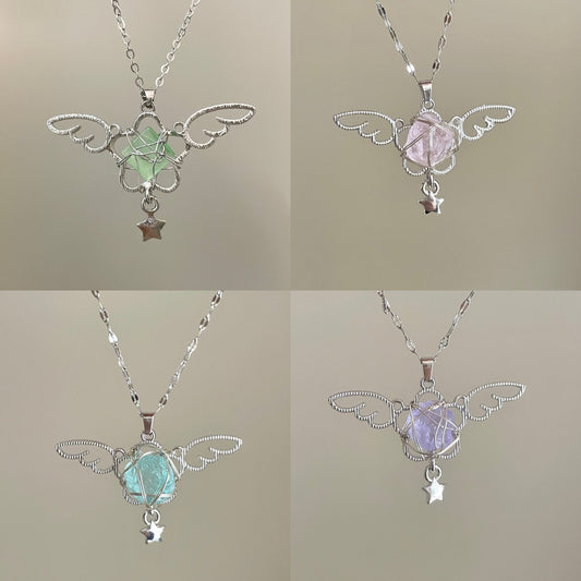 Four angel wing pendants with gemstones on a neutral background