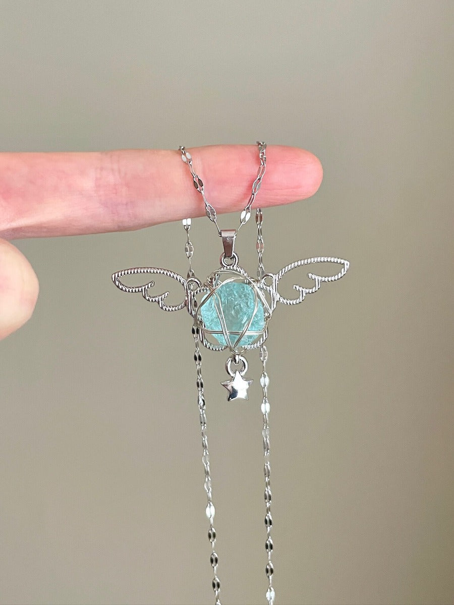 Silver necklace with a turquoise pendant held by a hand against a neutral background