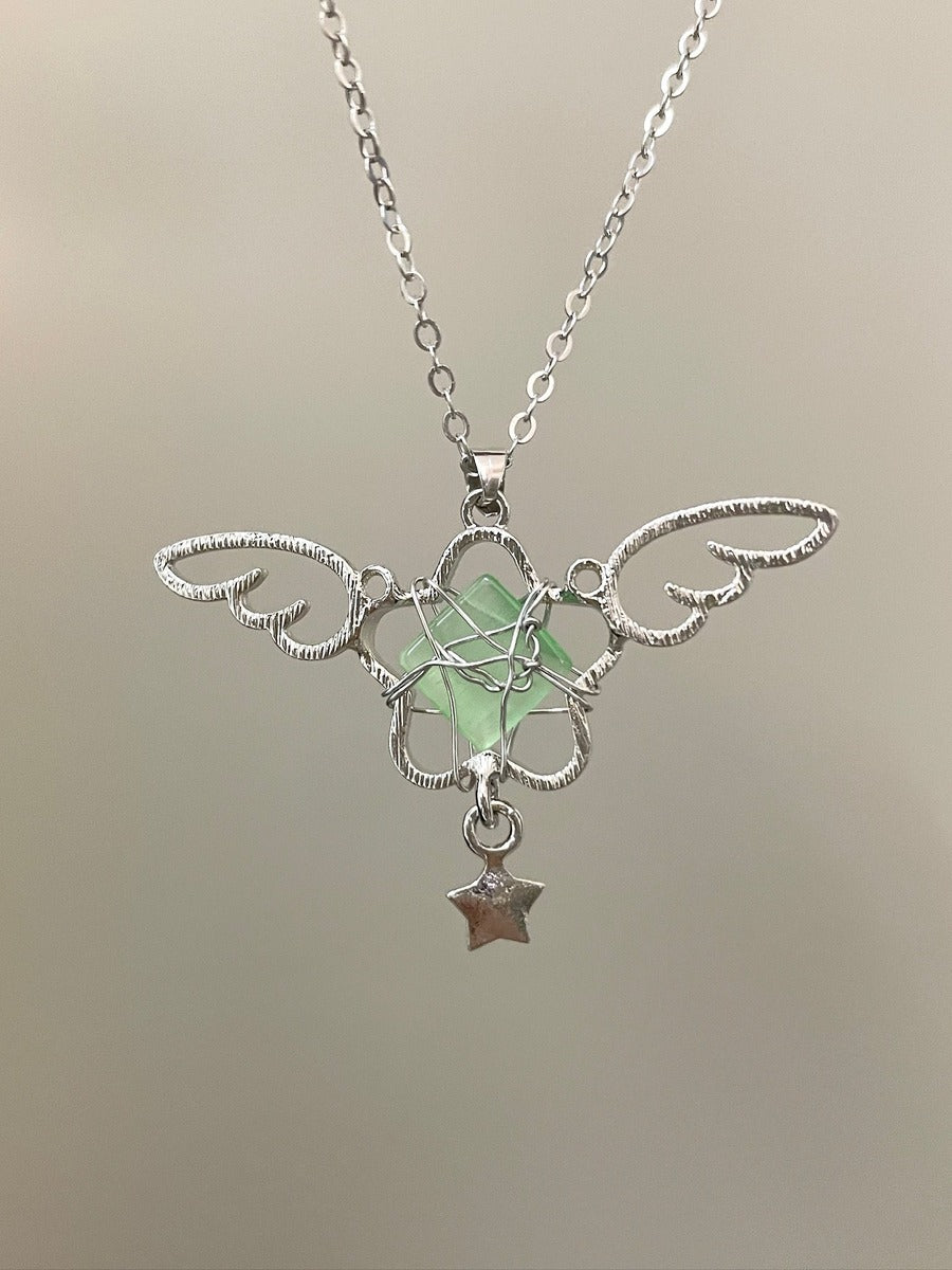 Silver necklace with a green pendant and star charm on a neutral background