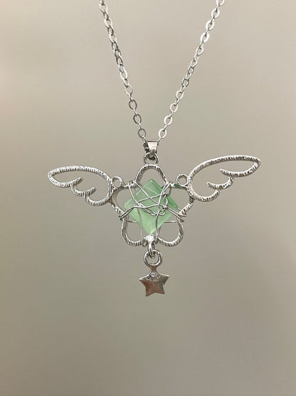 Silver necklace with a green pendant and star charm on a neutral background