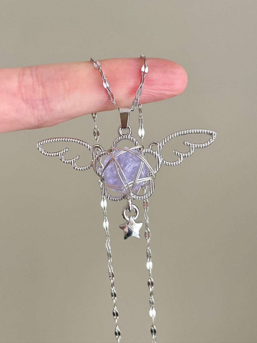 Silver pendant with a purple stone held by a hand against a neutral background