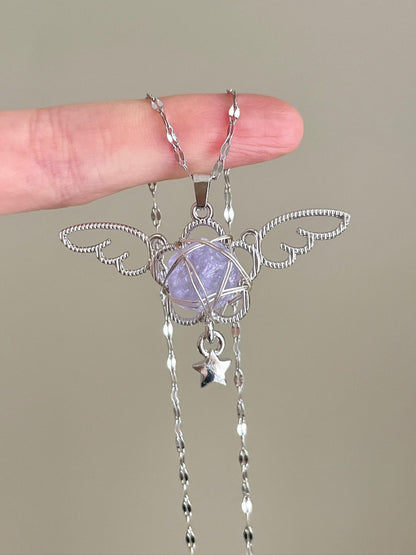 Silver pendant with a purple stone held by a hand against a neutral background