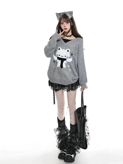Person wearing a gray sweater with a cat design, black skirt, and black shoes on a white background