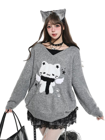 Woman wearing a gray sweater with a white cat design, holding a black handbag.