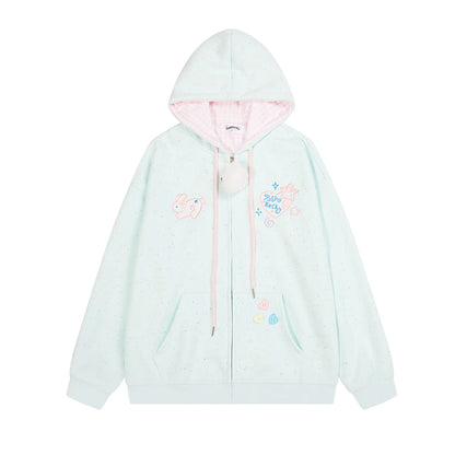 A pastel mint green zip-up hoodie with a pink inner hood lining, pink drawstrings, and cute cartoon bunny and unicorn graphics on the chest, displayed against a solid white background.