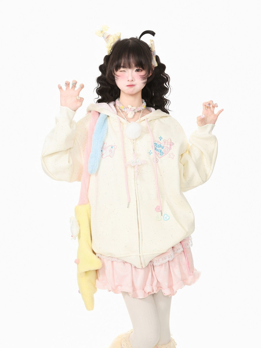 A model wearing a pastel-colored Lolita-style outfit, featuring a cream-colored zip-up hoodie with pink and blue accents, a pink ruffled skirt, and a yellow plush accessory, posed against a solid white background.