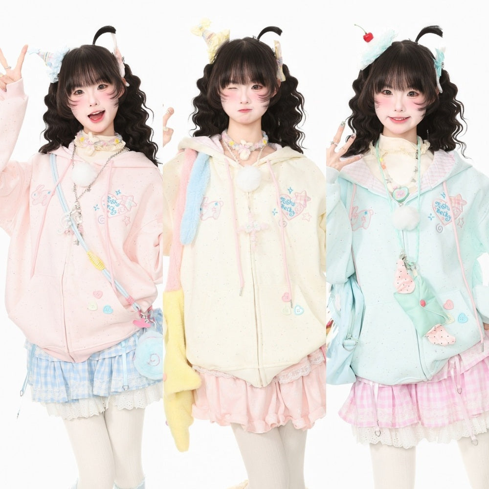 Three models wearing pastel anime-style hoodies in pink, cream, and light blue, each styled with matching pleated skirts, cute accessories, and face makeup against a white background.