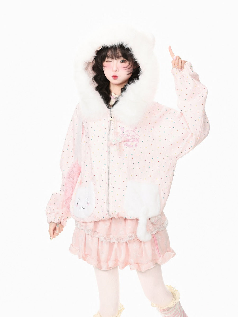 A model wearing a light pink polka-dot hooded jacket with white faux fur trim, a matching pink ruffled skirt, and white tights, posing against a solid white background.