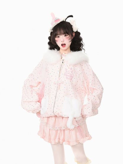 A young girl modeling a light pink bunny-themed jacket with white faux fur trim, matching pink ruffled skirt, and a bunny headband against a solid white background.