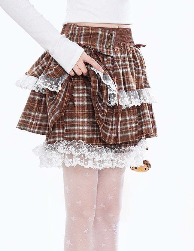 A brown and beige plaid pleated skirt with white lace ruffles, modeled with a white long-sleeve top and sheer white tights with star patterns.