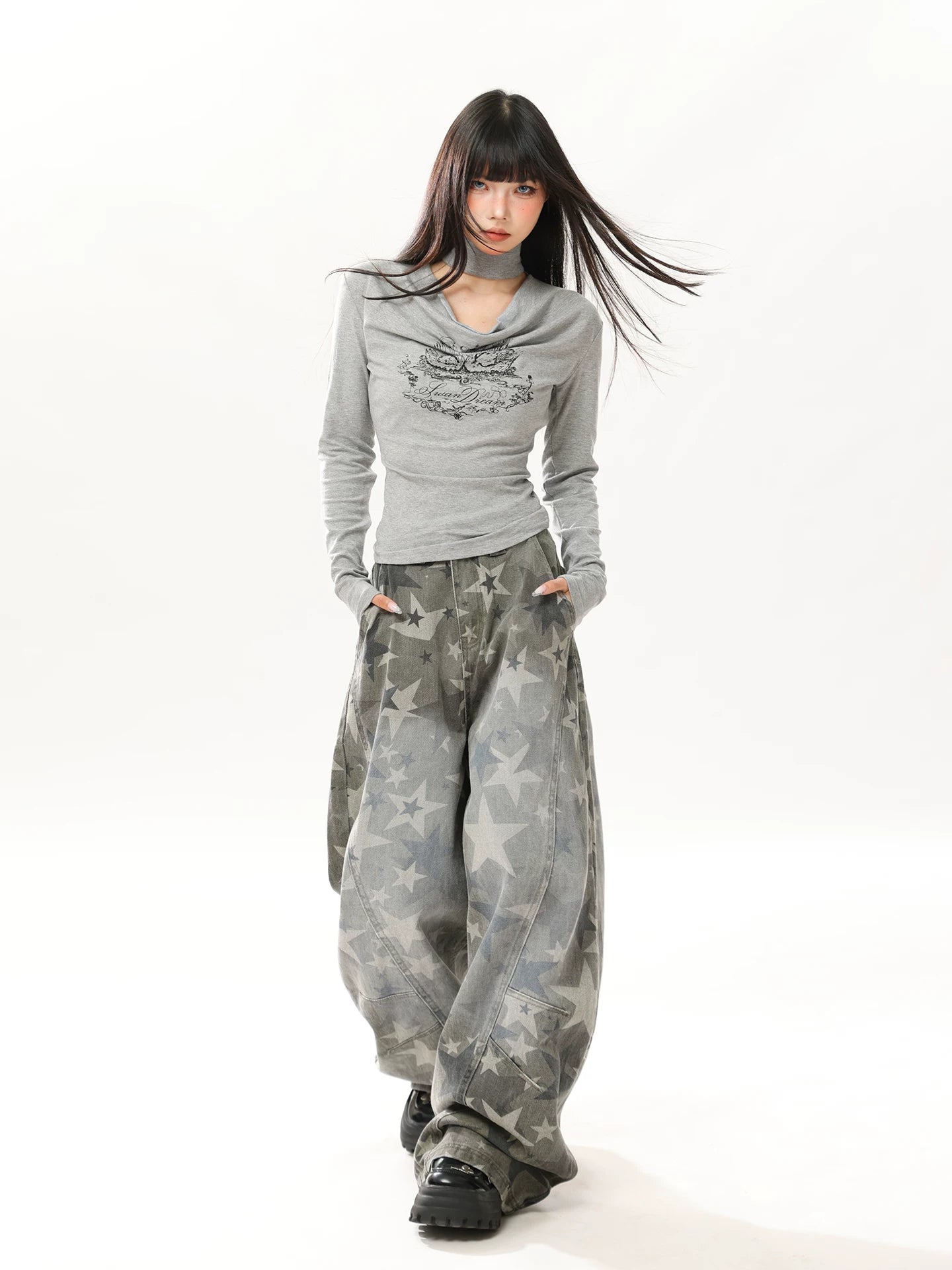 Woman wearing a gray long-sleeve top and camouflage pants on a white background