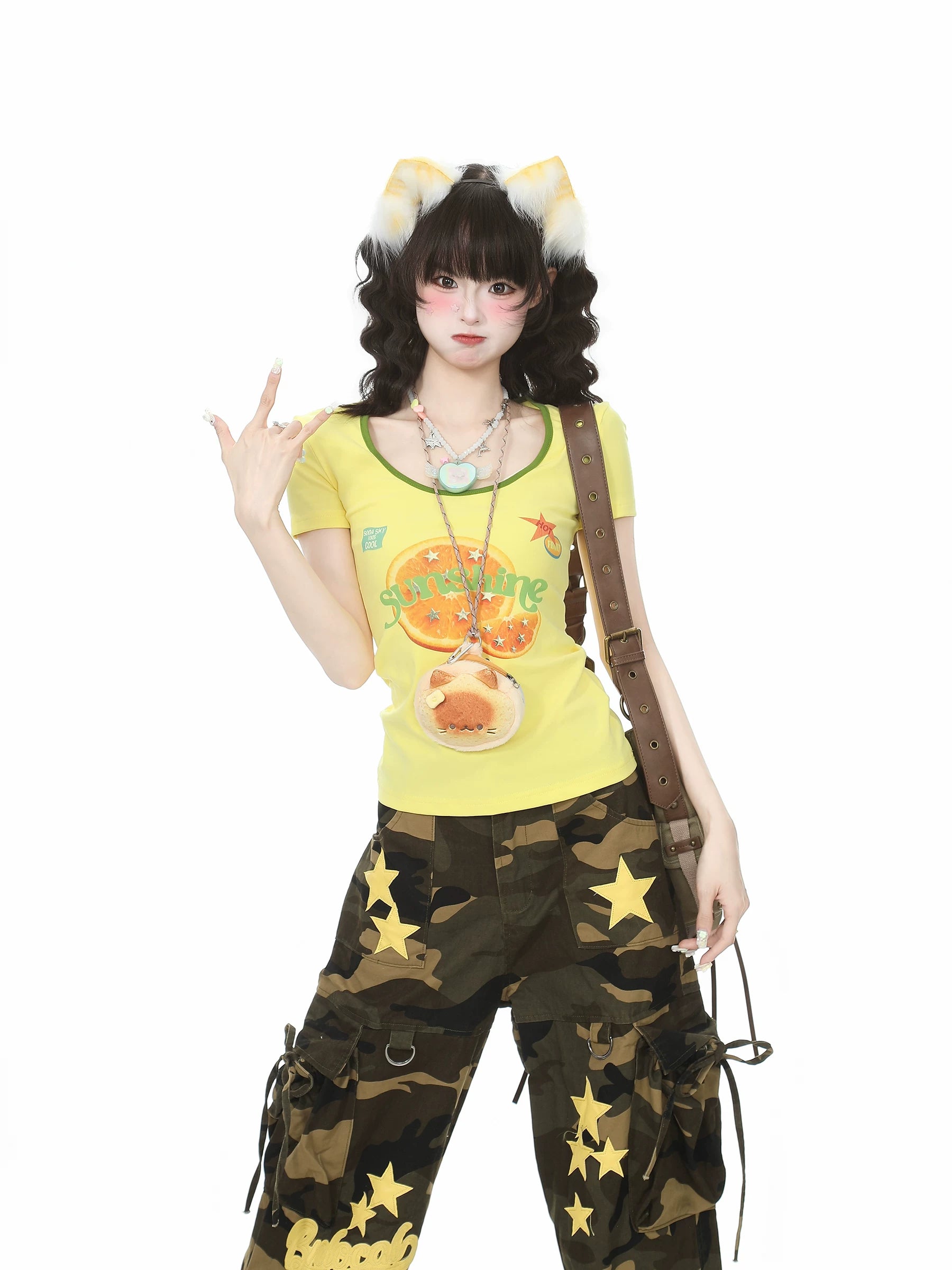 Person wearing a yellow top with cartoon character, camouflage pants with star patterns, and cat ears on a white background