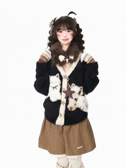 A young girl modeling a black fuzzy cardigan with faux fur trim, decorated with cat illustrations and a star applique, paired with a brown plaid pleated skirt against a plain white background.