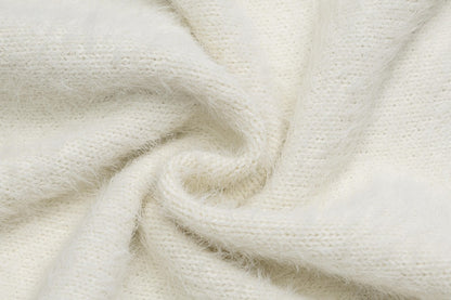 A close-up of soft, fluffy knit fabric in a warm off-white or cream color, arranged in a gentle swirl to show texture and drape.