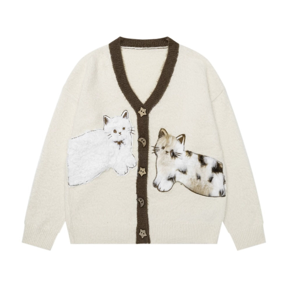 An off-white knit cardigan sweater featuring a dark brown V-neck trim and button placket, decorated with two embroidered cats on the front.