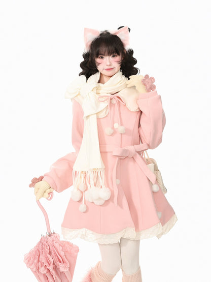 A young woman modeling a cute pink winter outfit with a matching pink coat, cream scarf, cream gloves, and pink accessories against a plain white background.